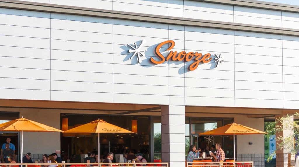 An Exterior Photo Of The Snooze Restaurant & Patio At Ahwatukee Showing The Snooze Sign