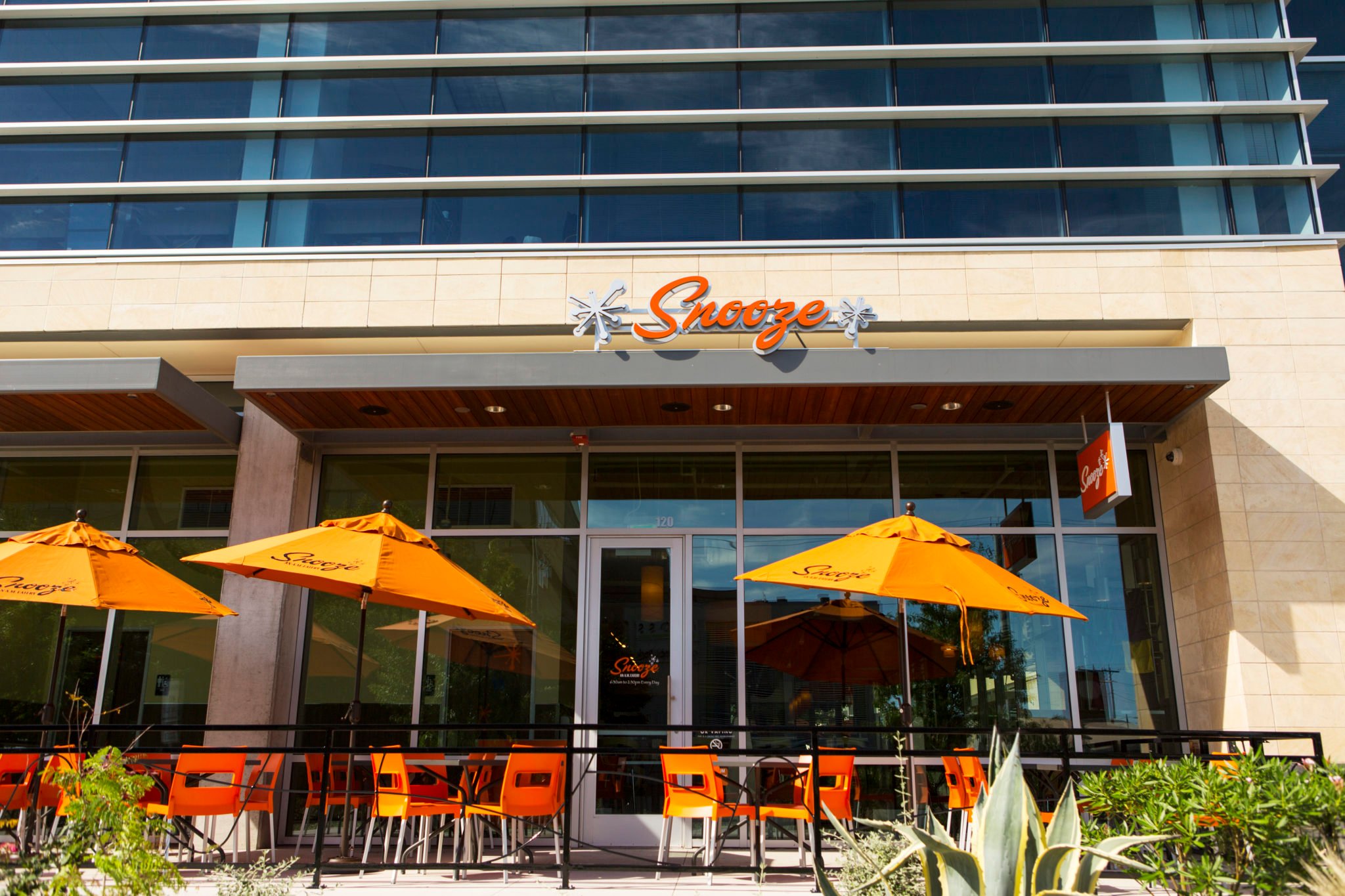 An Exterior Photo Of The Snooze Restaurant & Patio In North Lamar Showing The Snooze Sign