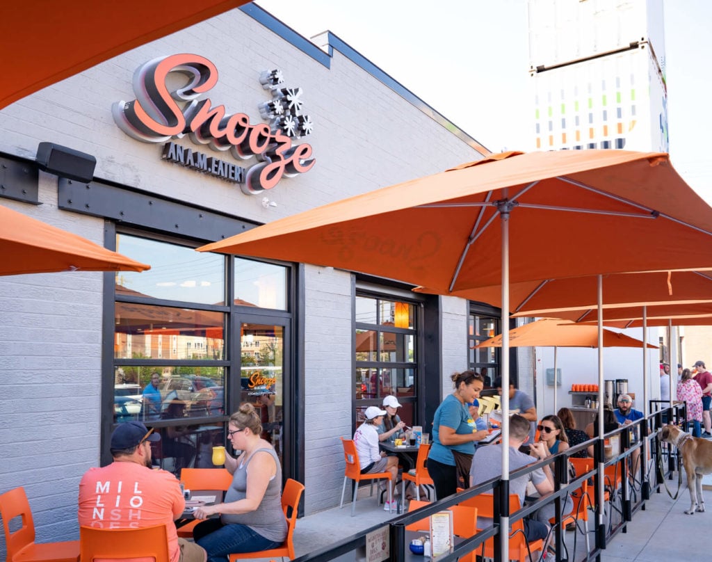 An Exterior Photo Of The Snooze Restaurant & Patio At Plaza Midwood Showing The Snooze Sign